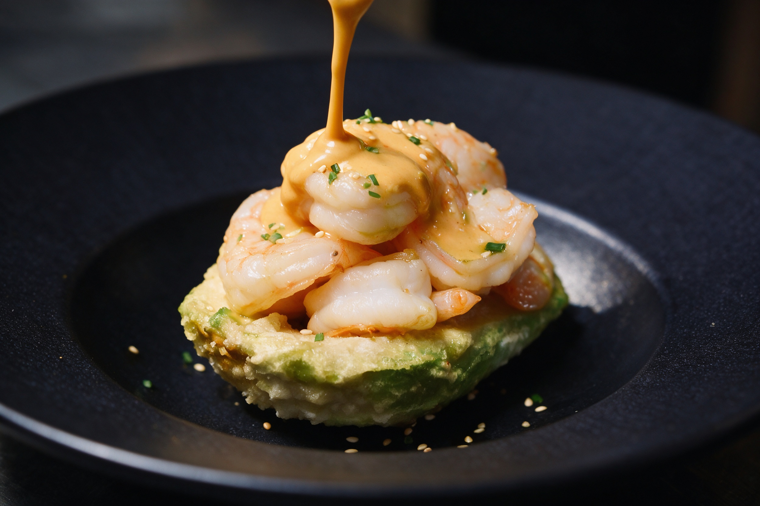 Tempura de aguacate con langostinos sobre salsa de naranja en plato de autor de ATIPIKO